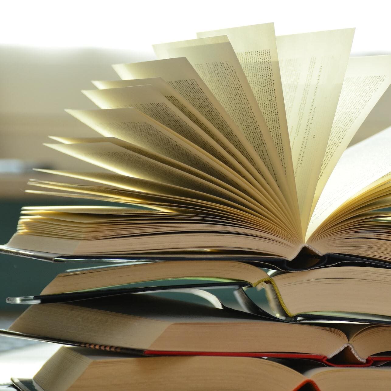 Books flipped open on a table with light coming through the pages.