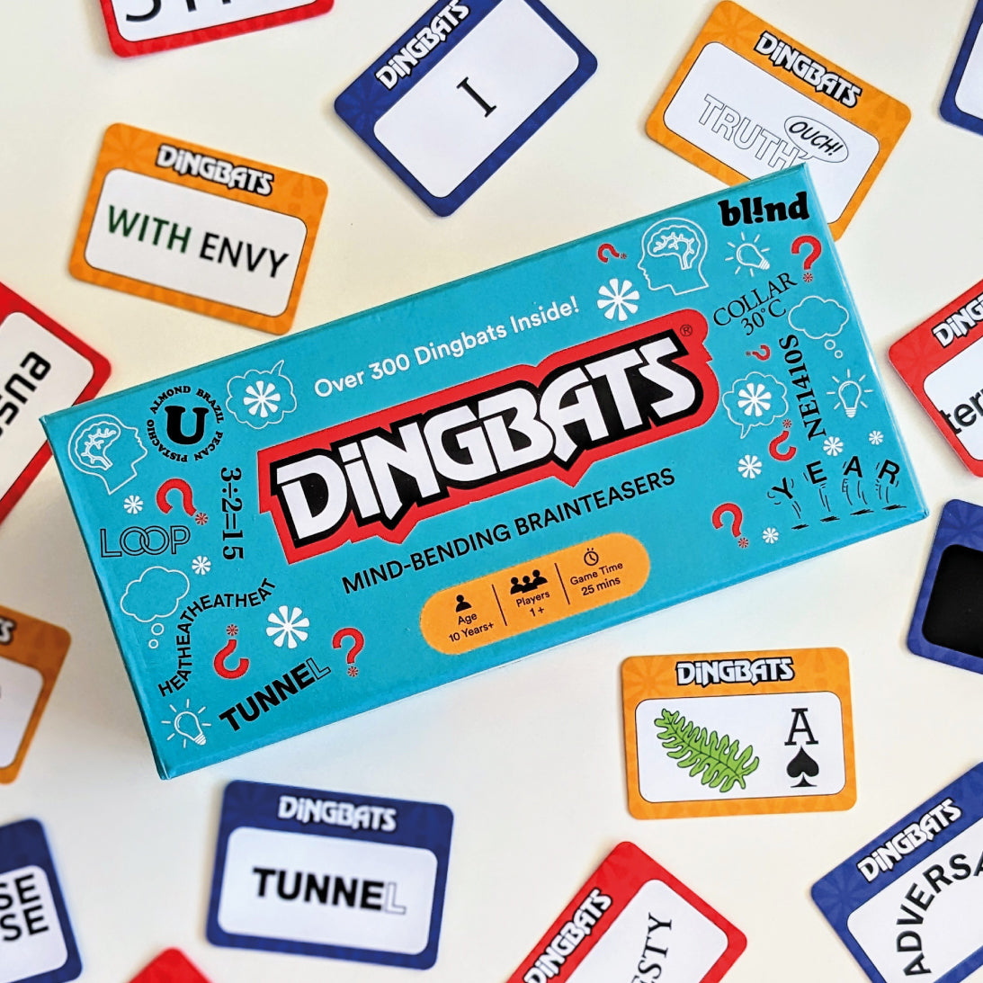 The product box for the card game 'Dingbats' is shown from an overhead angle, surrounded by various colourful card faces on a white background.