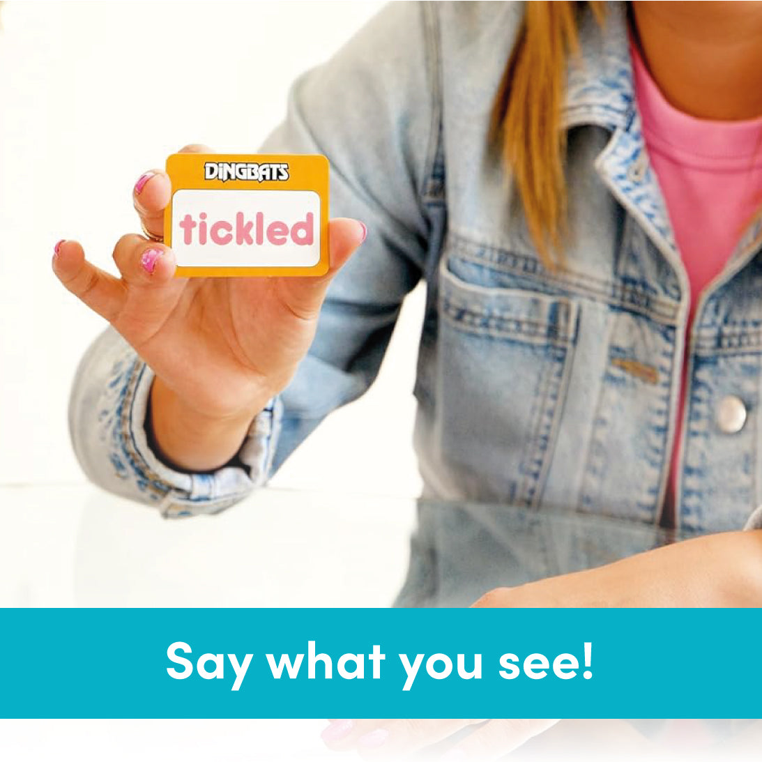 A person in a denim jacket holds up a DINGBATS branded card that says 'tickled' against a white background, with a teal banner at the bottom reading 'Say what you see!'.