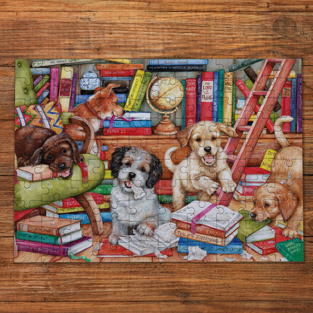 A completed jigsaw puzzle featuring several playful dogs surrounded by books, a globe, a ladder, and furniture, displayed on a wooden surface.