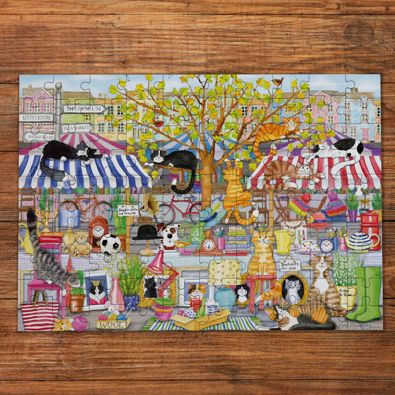 Jigsaw puzzle with a colorful scene of cats in various settings on a wooden surface