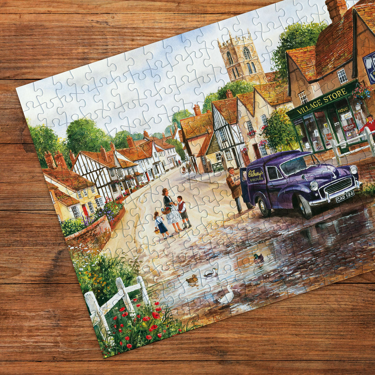 Jigsaw puzzle of a village scene with a purple van on a wooden surface