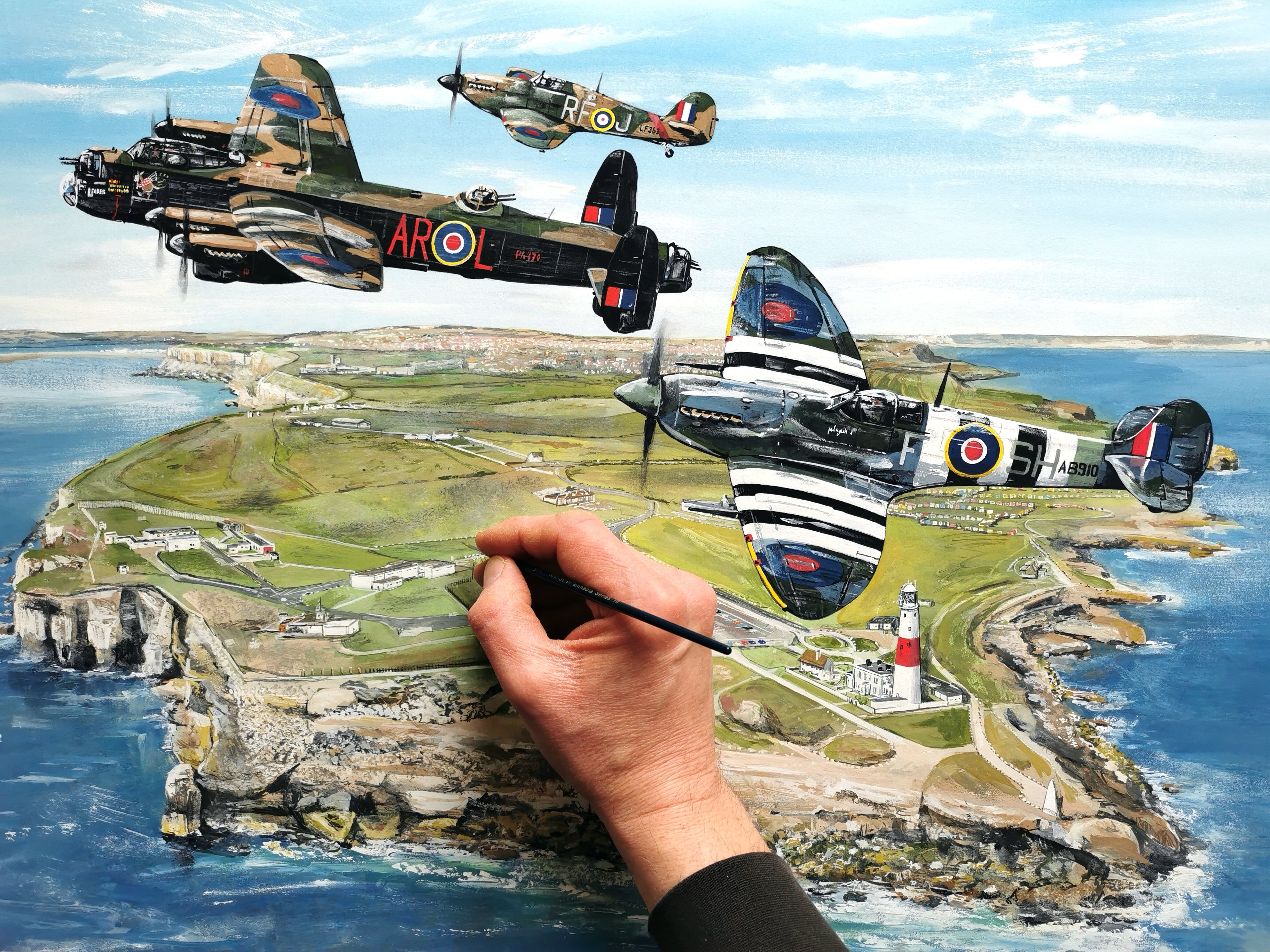 Painting of vintage airplanes over a coastal landscape with a hand holding a paintbrush.