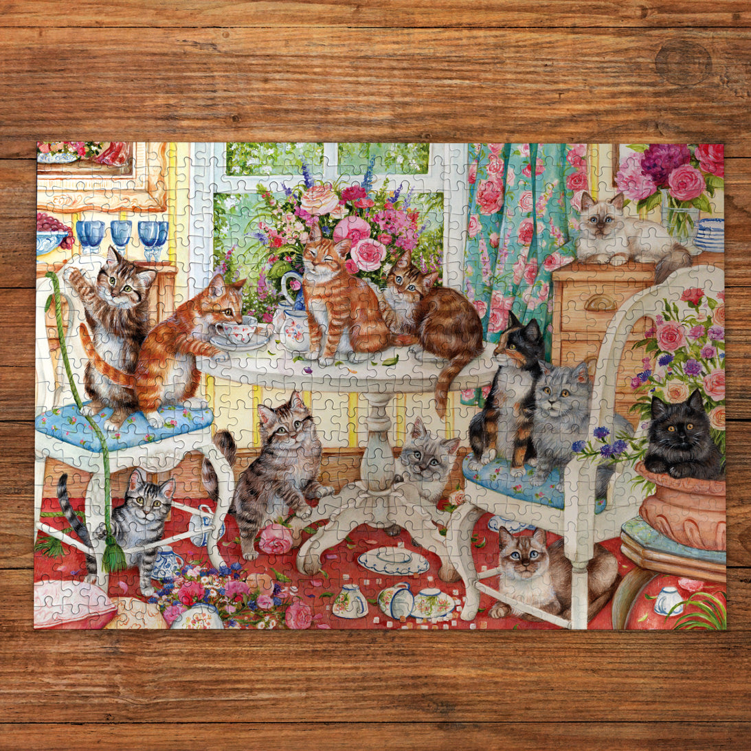 Jigsaw puzzle with a design of cats around a table on a wooden surface