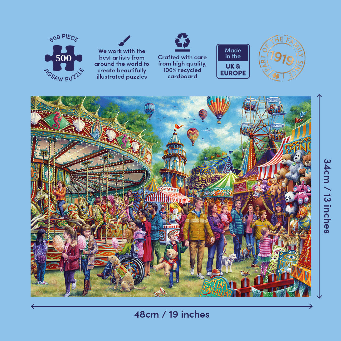 A 500-piece jigsaw puzzle box featuring a colourful fairground scene with carousel, tents, balloons, and people. The box is shown on a light blue background with printed dimensions (48cm x 34cm / 19 inches by 13 inches) and feature icons.