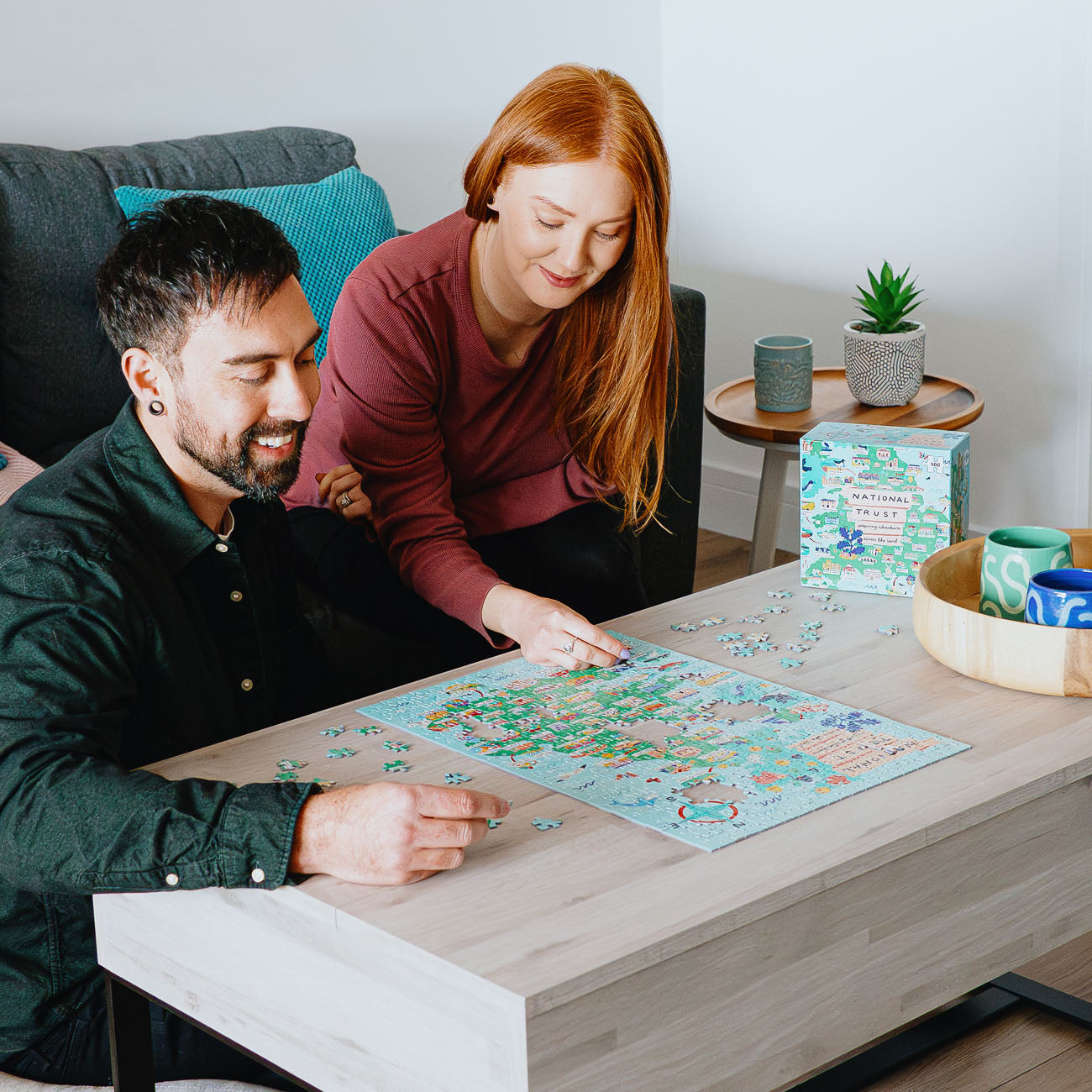 Man and woman working on a puzzle together at a table in a cozy living room.