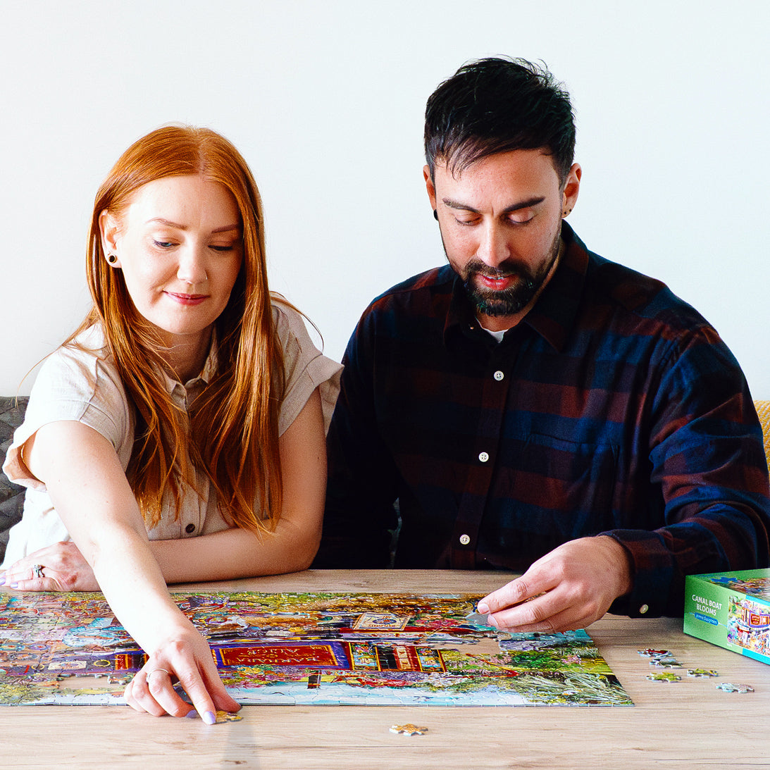 Man and woman working on a puzzle together at a table.