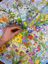 Hand placing a puzzle piece on a colorful garden-themed puzzle