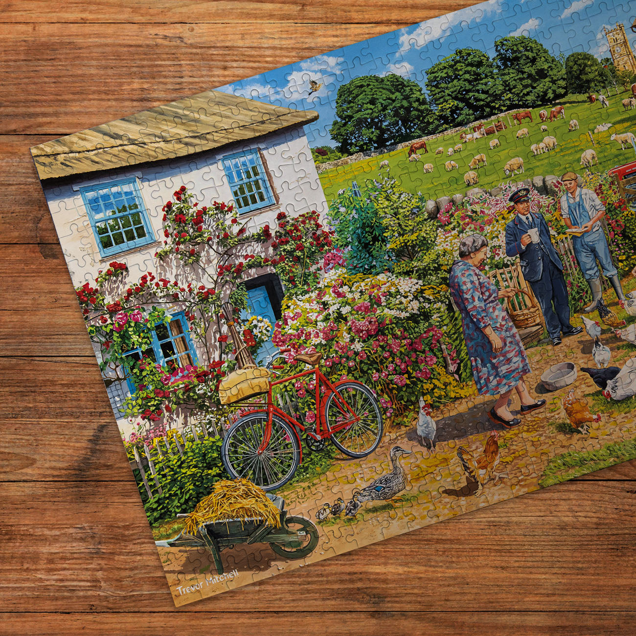 Jigsaw puzzle with a scenic countryside design featuring a house, garden, and people on a wooden surface.