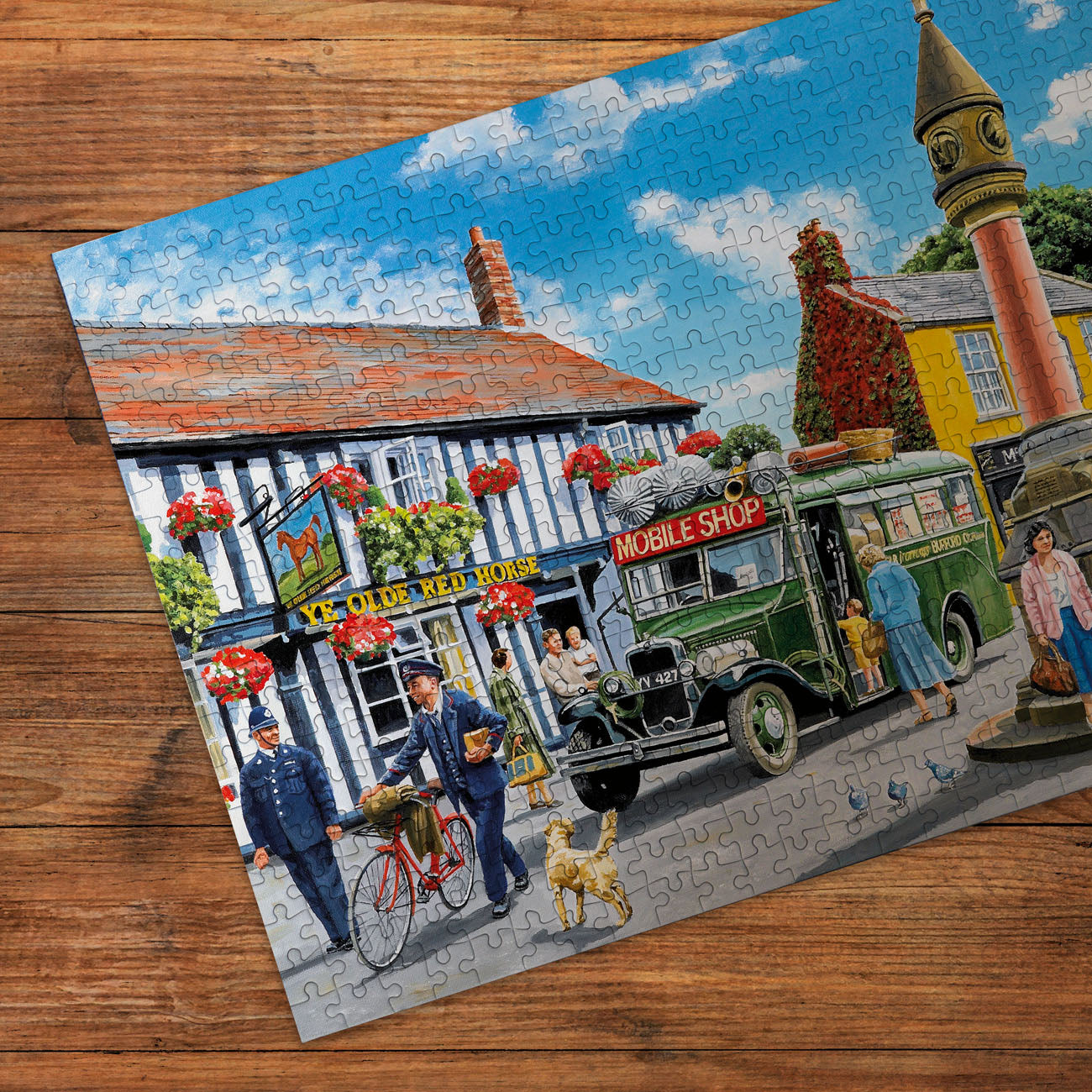 Jigsaw puzzle with a colorful scene of a town square featuring a mobile shop and people on a wooden surface.