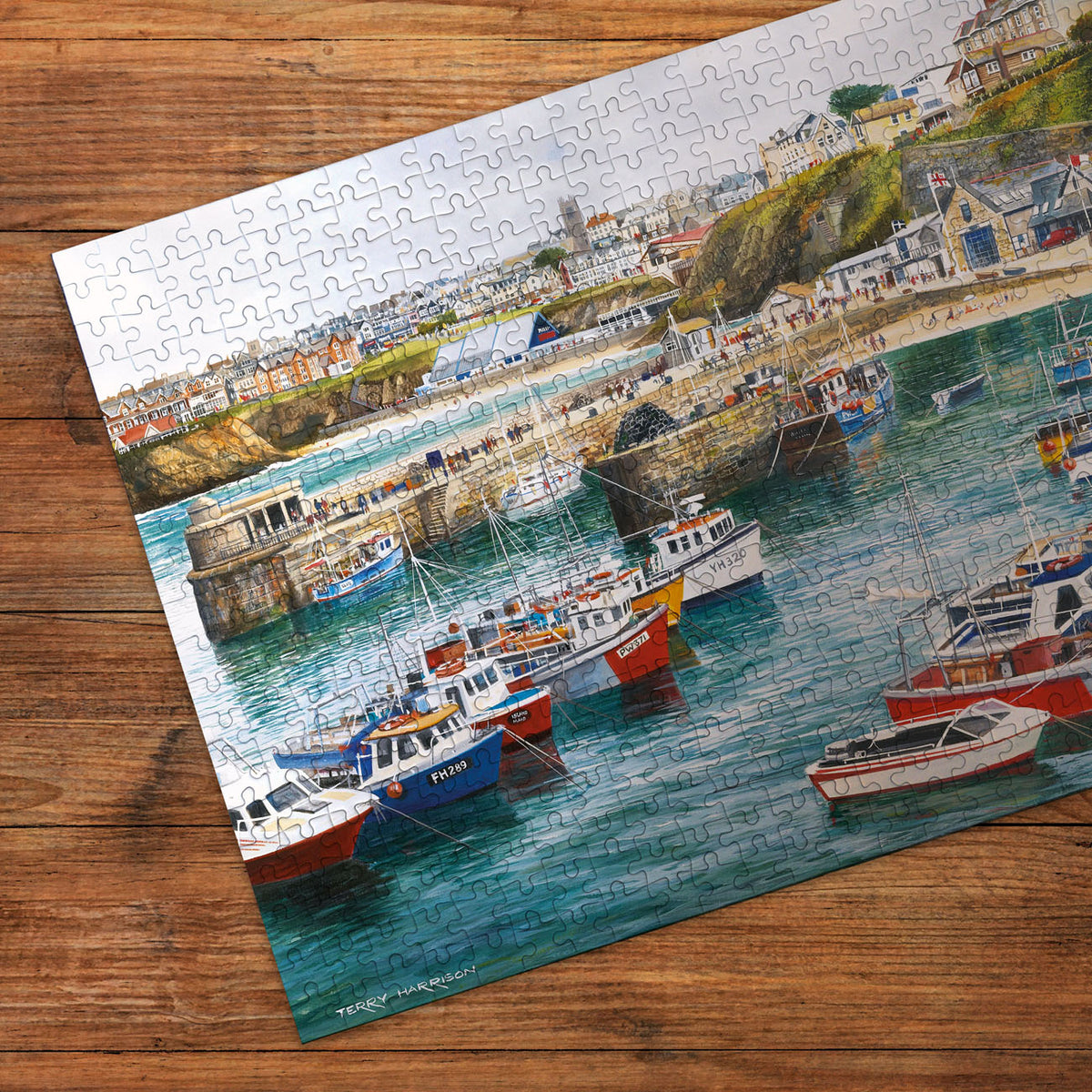 Jigsaw puzzle with a completed scene of boats in a harbor on a wooden surface