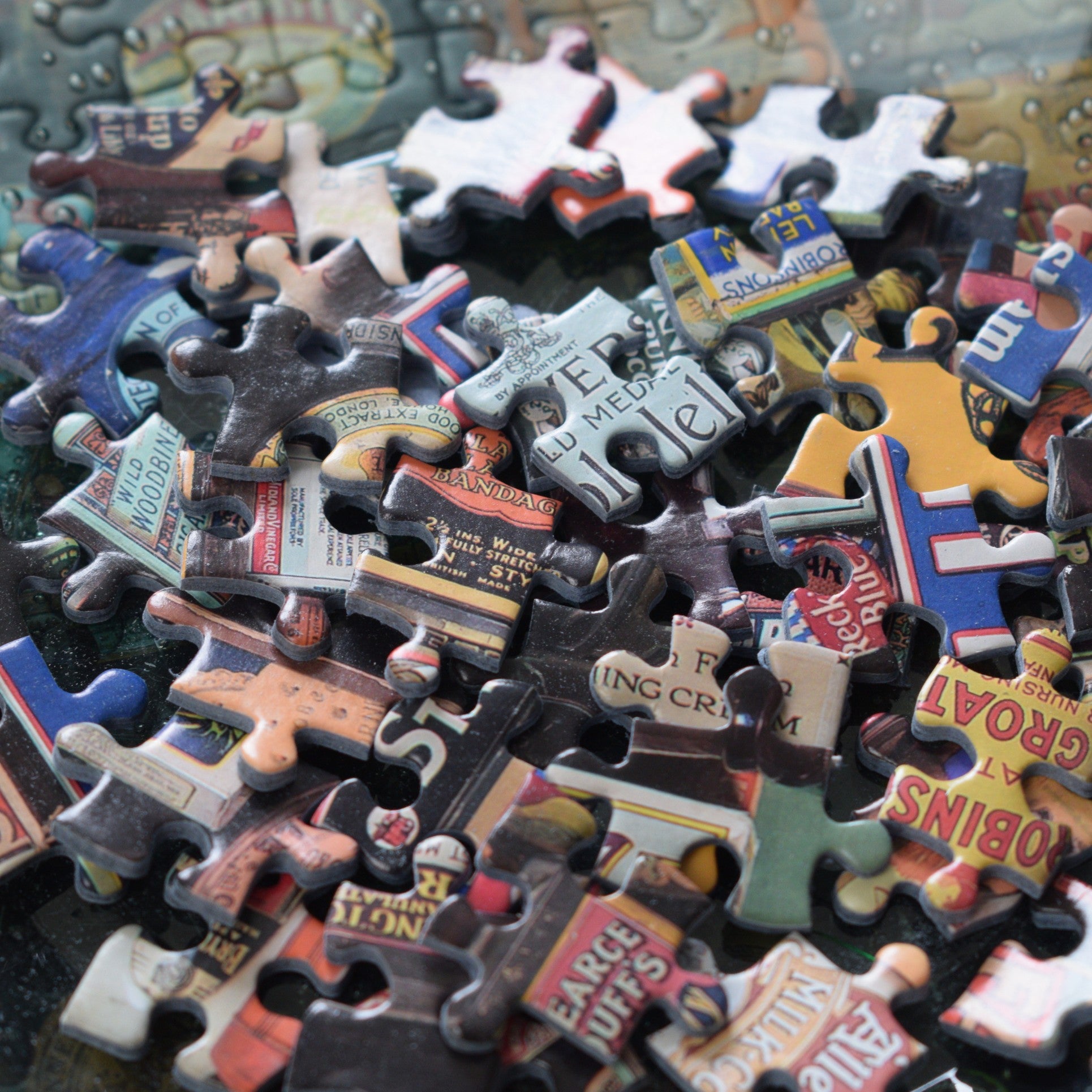 A close-up pile of jigsaw puzzle pieces featuring vintage street signs, letters, and colourful text elements scattered together.