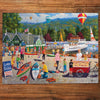 Jigsaw puzzle with a lake scene featuring people, boats, and hot air balloons on a wooden surface.