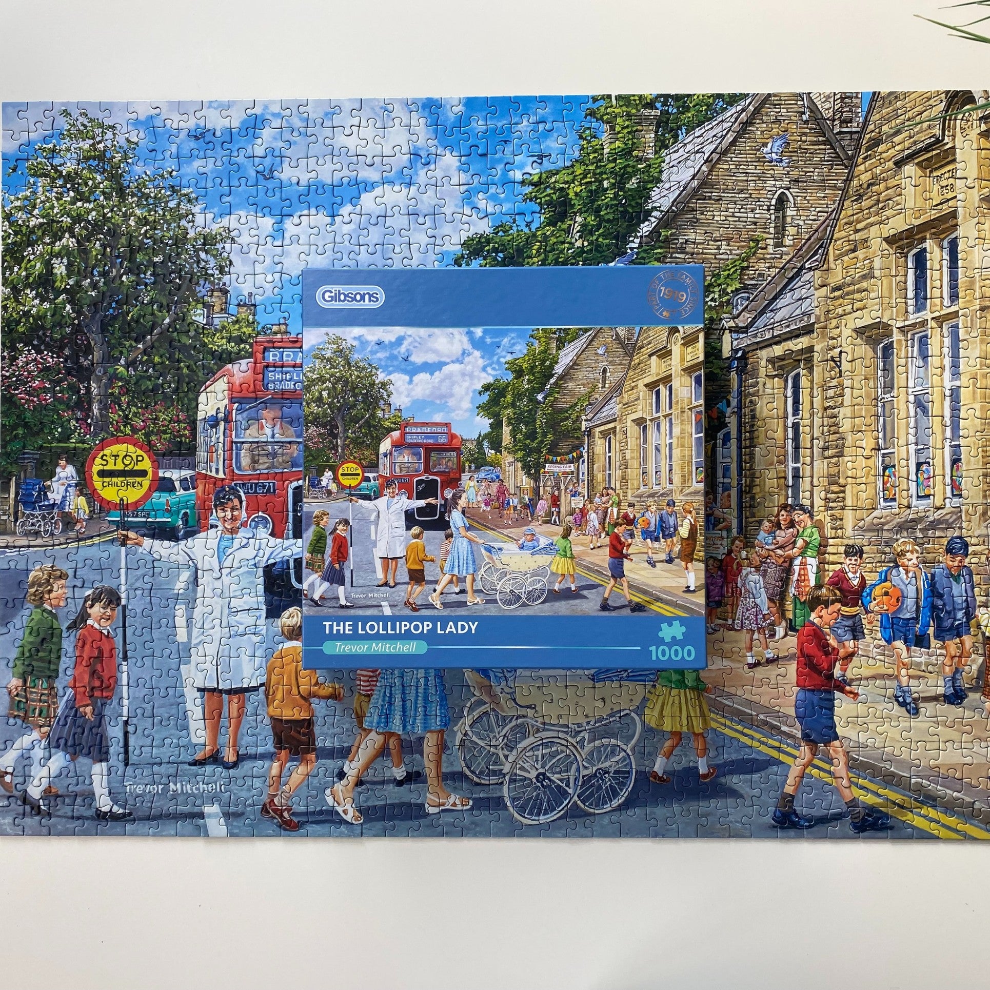 A completed 1000-piece jigsaw puzzle of 'The Lollipop Lady' by Gibson, depicting a busy street scene with a woman pushing a cart, set against a white background.