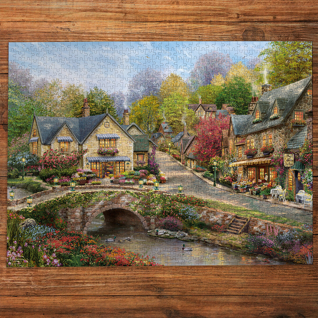 Summer in Cobblestone Village 1000 Piece Jigsaw Puzzle by Gibsons made up on wooden table