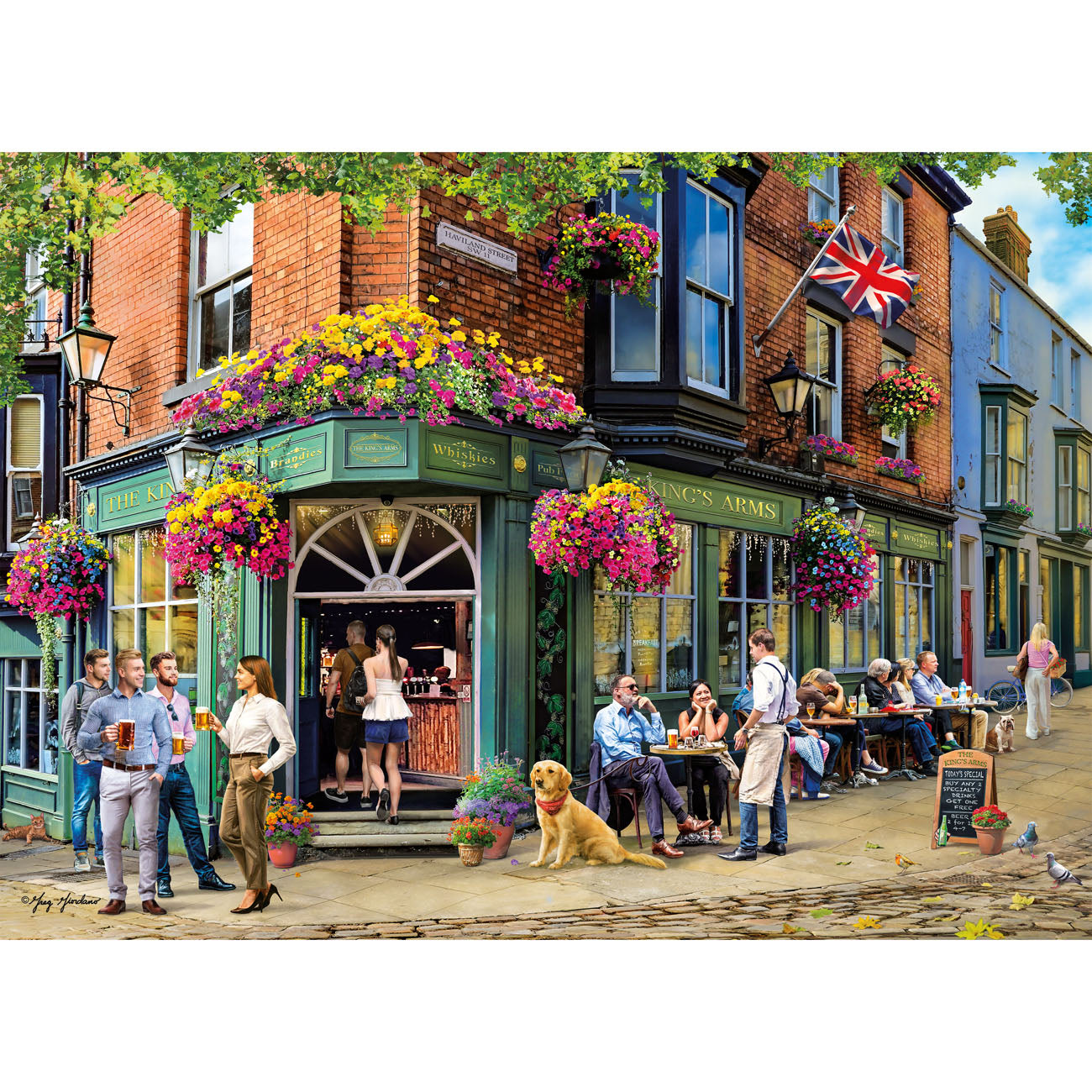 People gathered outside a pub with flowers and a British flag, on a sunny day.