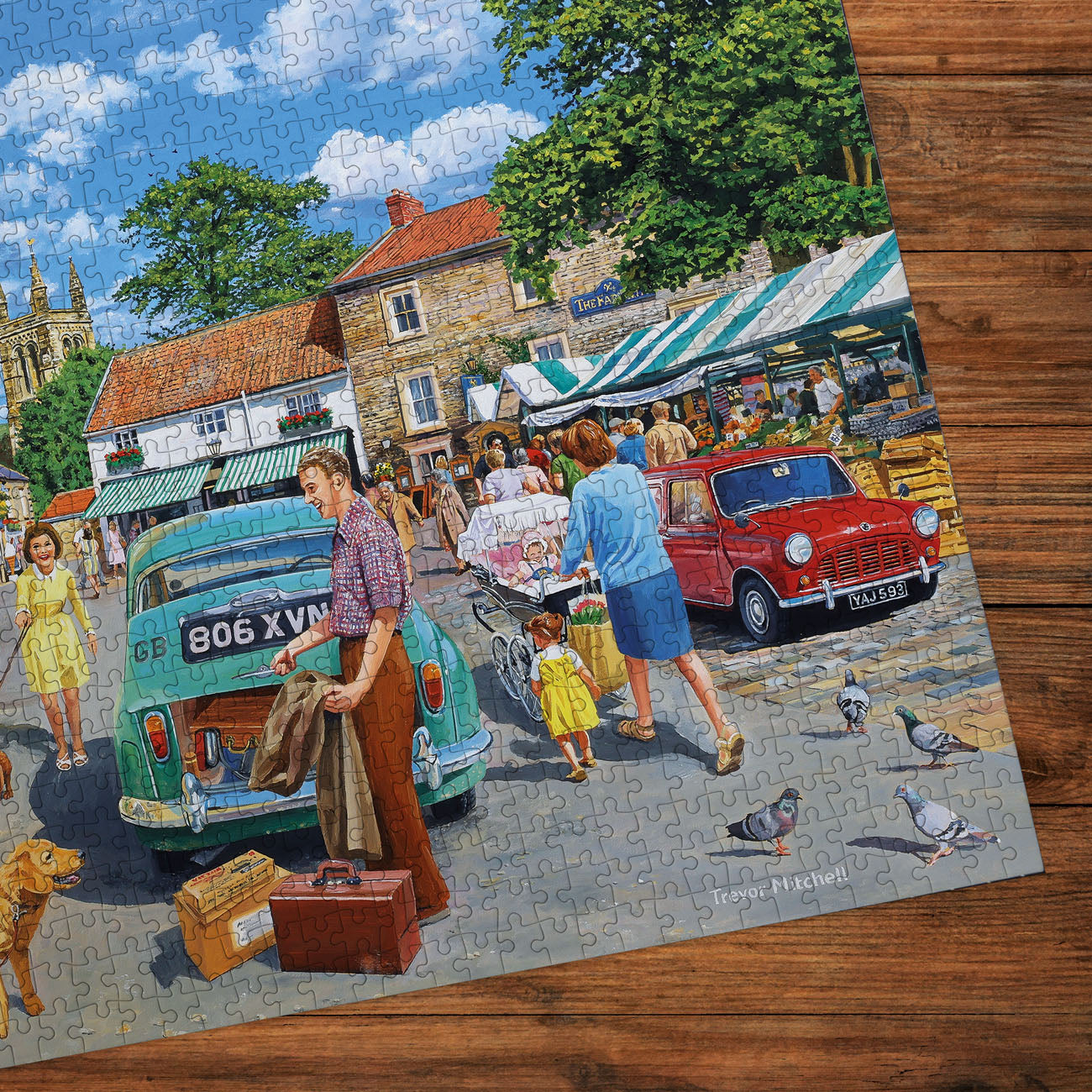 Jigsaw puzzle of a village scene with people and cars on a wooden surface