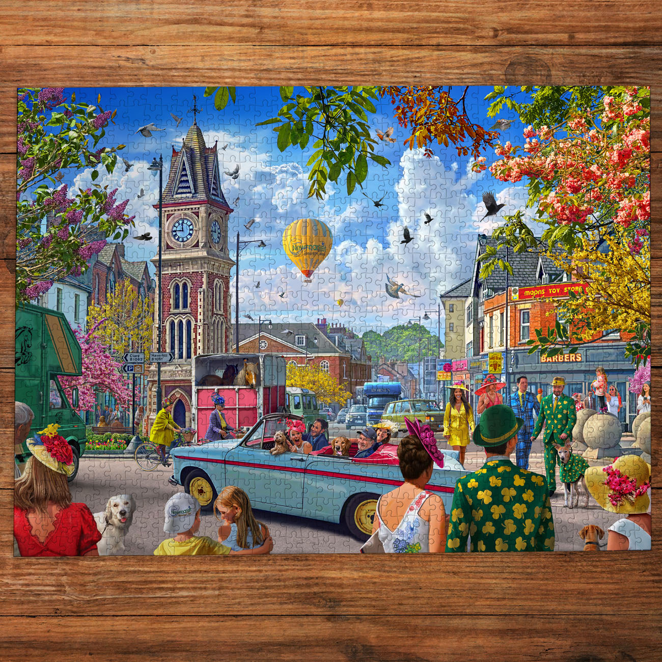 Colorful scene of a town square with people, cars, and a hot air balloon on a wooden table