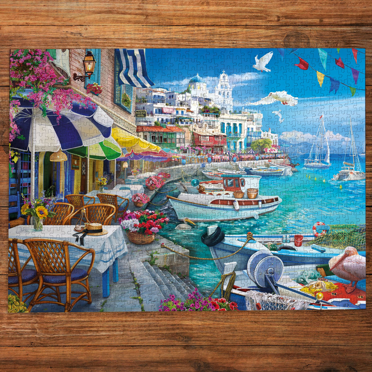 Colorful coastal scene with buildings, boats, and tables on a wooden surface