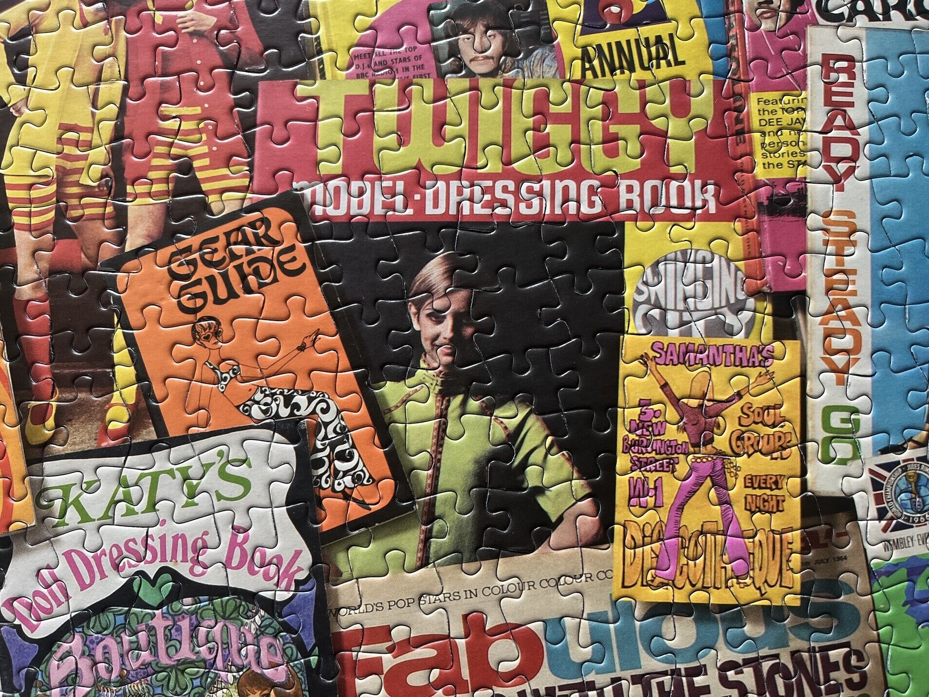 Jigsaw puzzle with colourful pieces featuring text and images, including Twiggy in a green shirt.