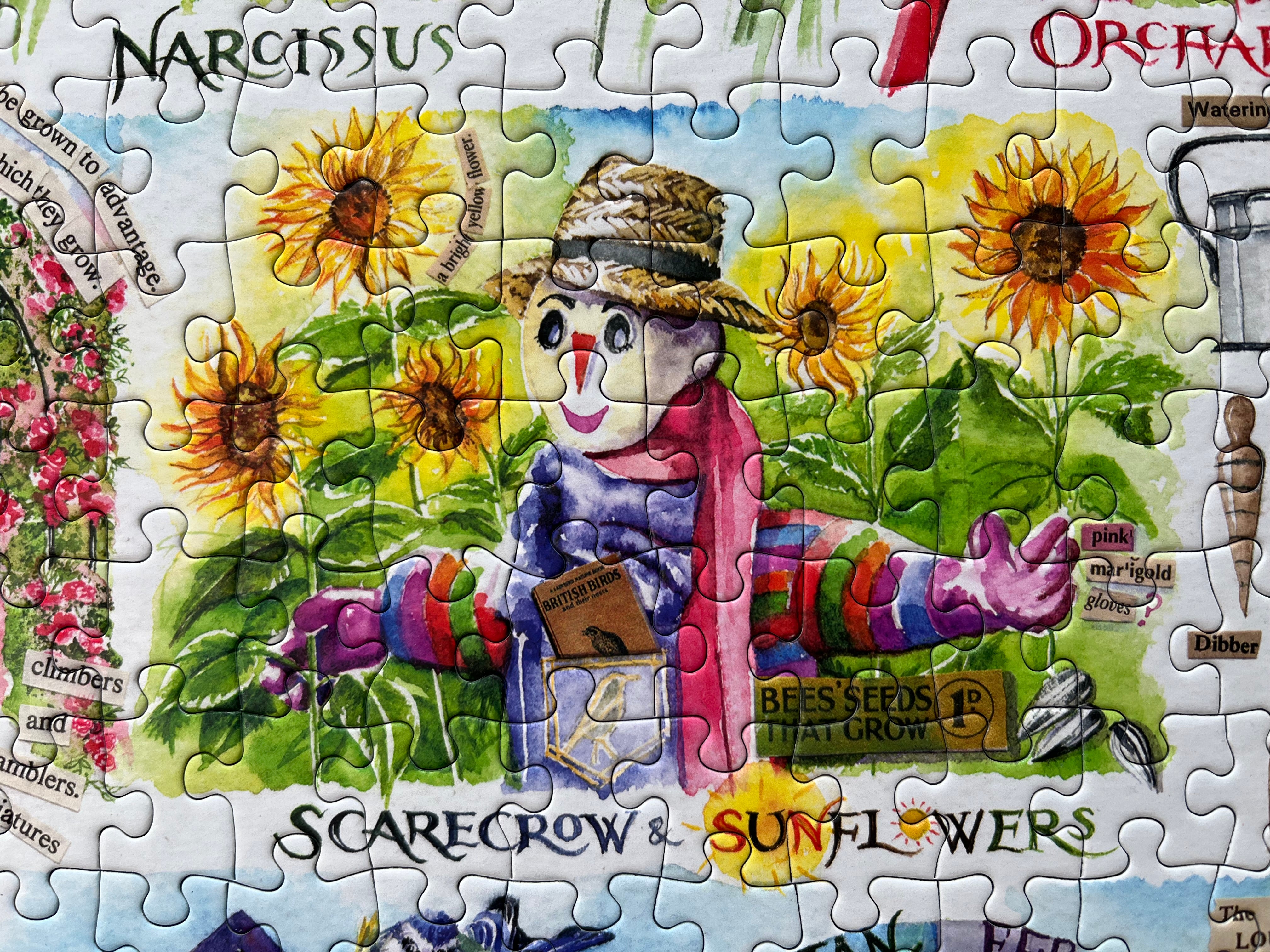 A colourful jigsaw puzzle featuring a cheerful scarecrow among bright sunflowers, with garden-themed text and illustrations around the border.