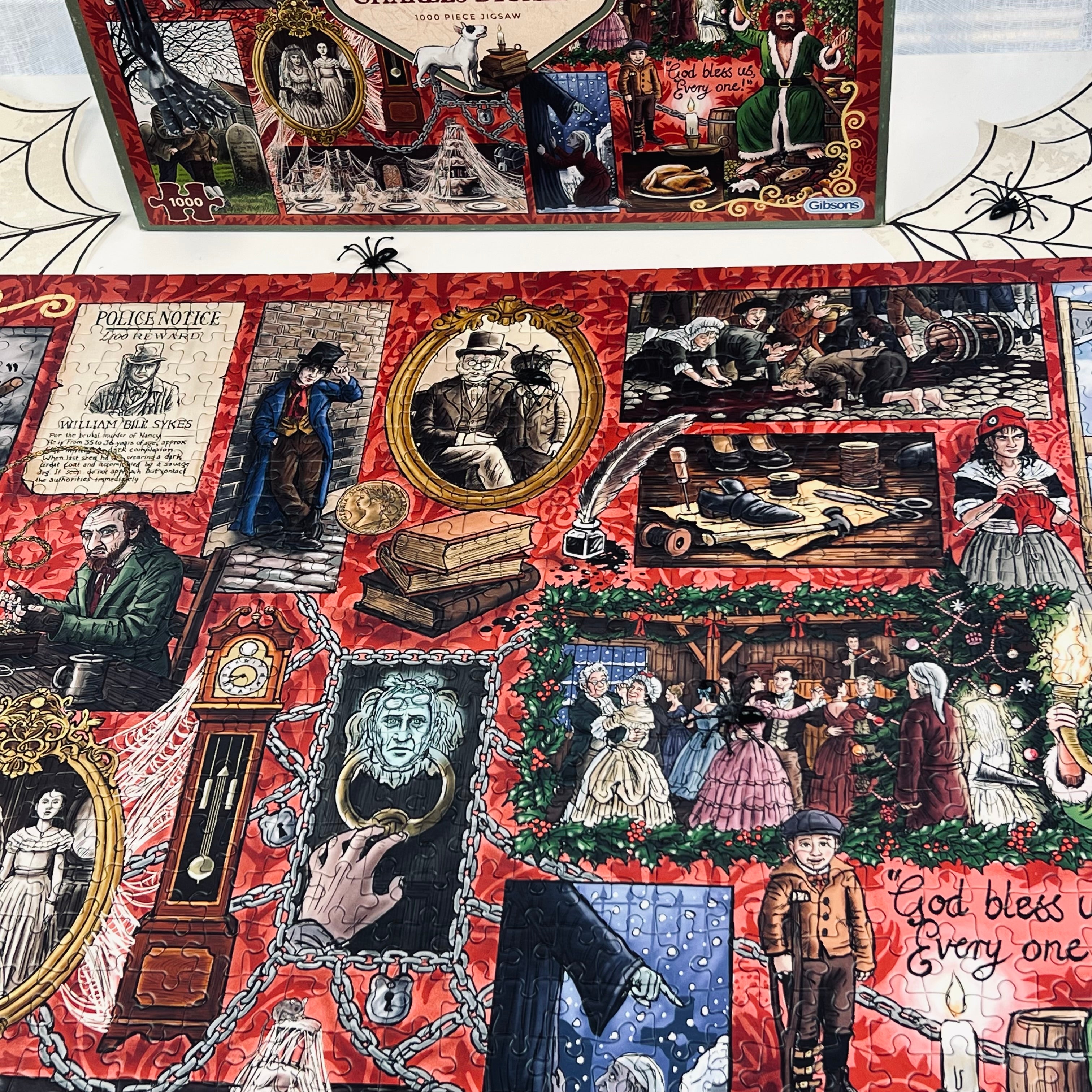 A red Halloween-themed jigsaw puzzle featuring a collage of vintage ghostly and spooky illustrations, including a police officer, a skeleton, a raven, a clock, chains, and the phrase 'God bless us every one.' A matching printed box is partially visible above the fabric.