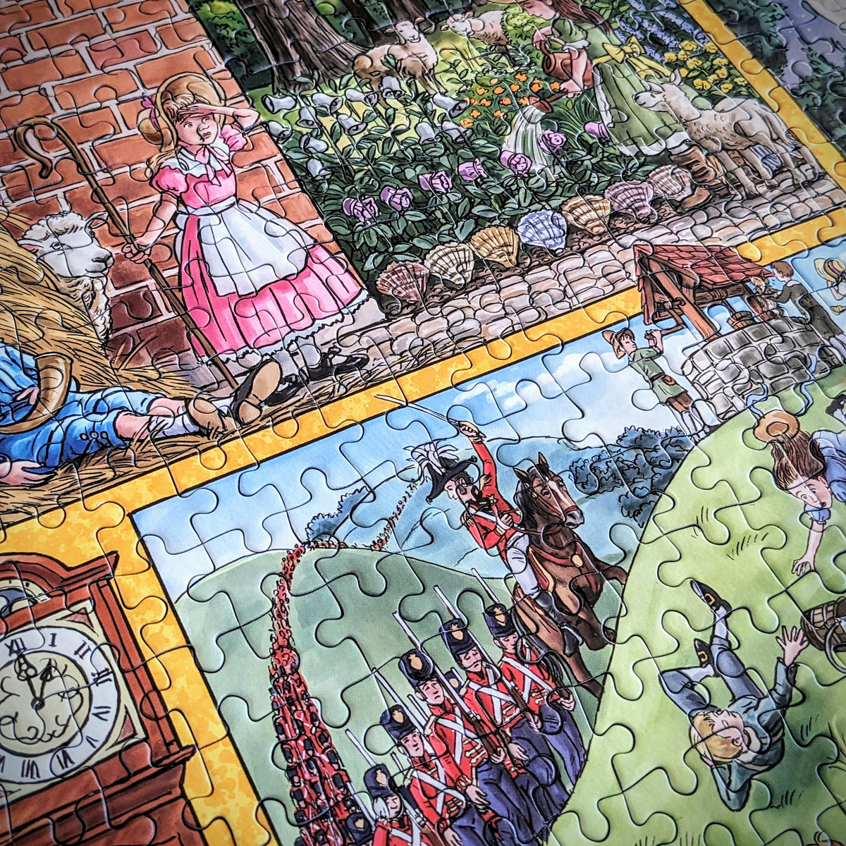 A close-up of a colourful illustrated jigsaw puzzle showing multiple scenes: a girl in a pink dress by a brick wall, flowers and animals in a garden, a clock face, soldiers in red uniforms, and other vintage-style drawings separated by puzzle-piece seams.