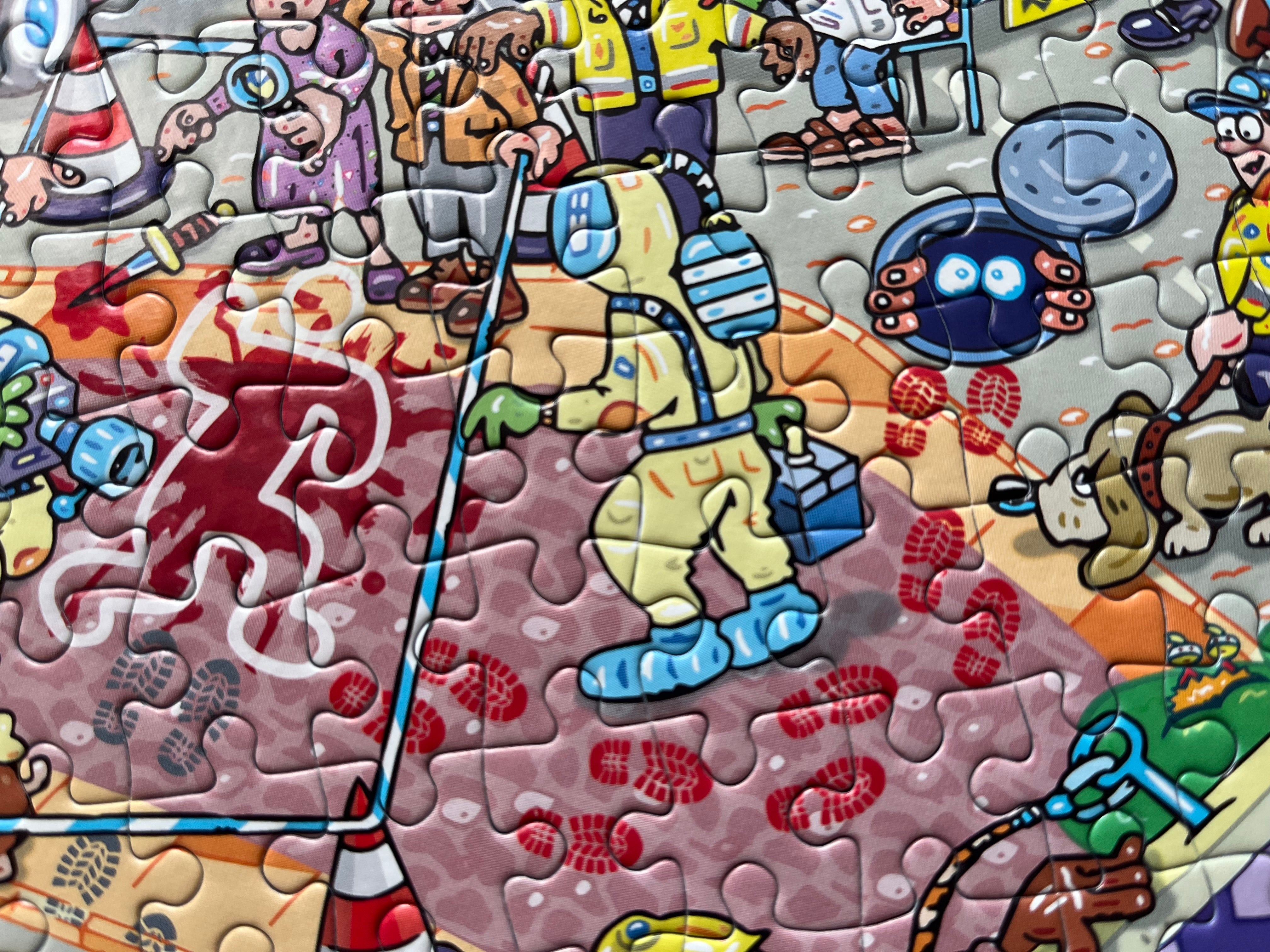 A close-up of a colourful jigsaw puzzle showing a cartoon-style illustrated scene with a yellow-suited figure, red footprints, a dog, traffic cones, and other characters.