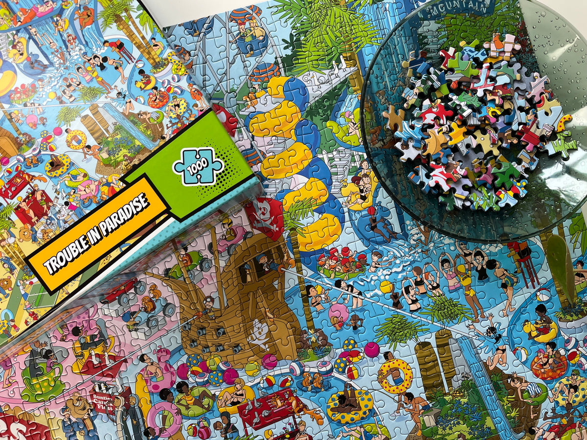 Jigsaw puzzle with a colorful design, partially completed, and a box labeled 'Trouble in Paradise'.