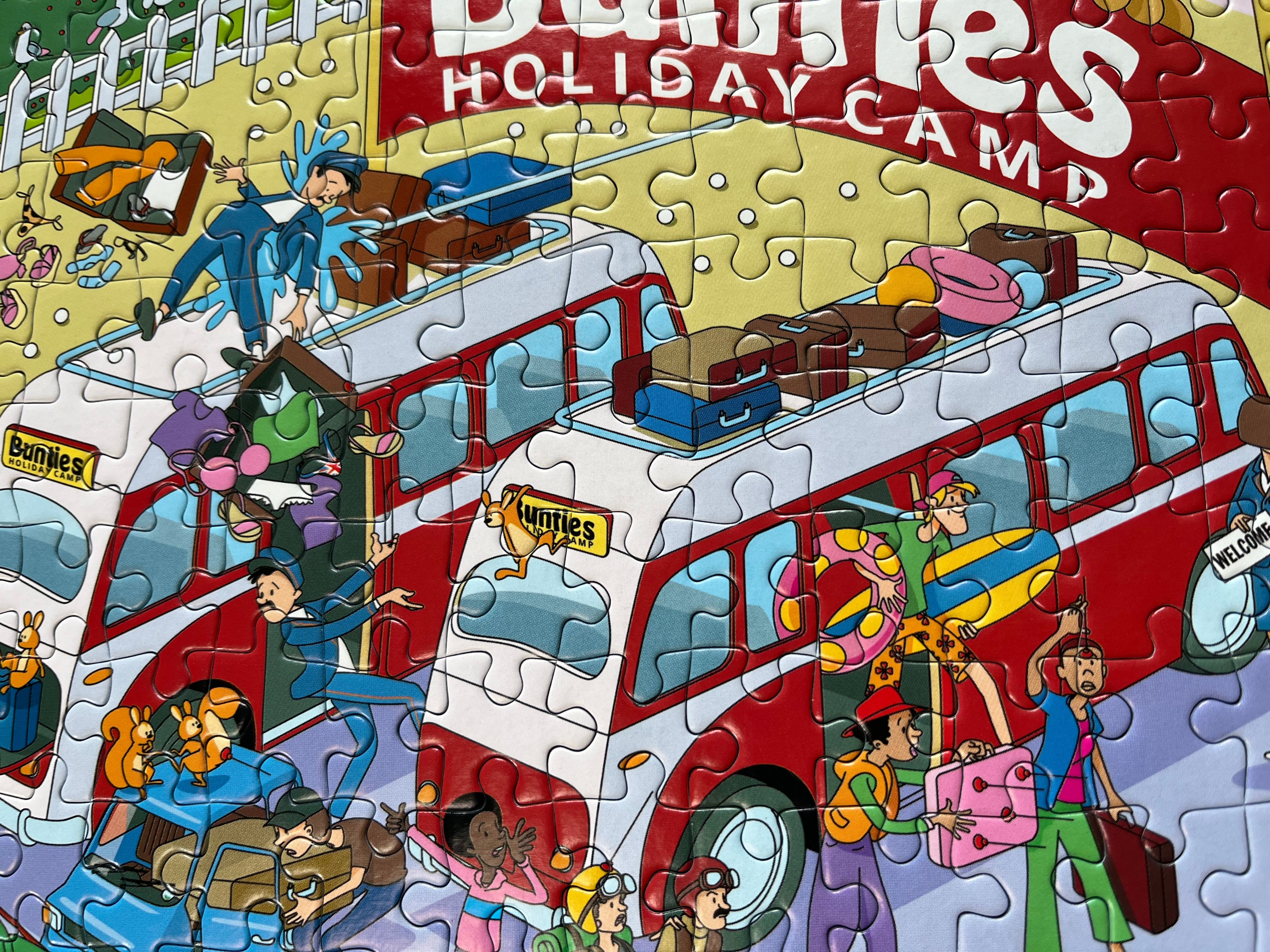 Jigsaw puzzle of a red double-decker bus with people on a yellow background, featuring the text 'Bumbles Holiday Camp'.