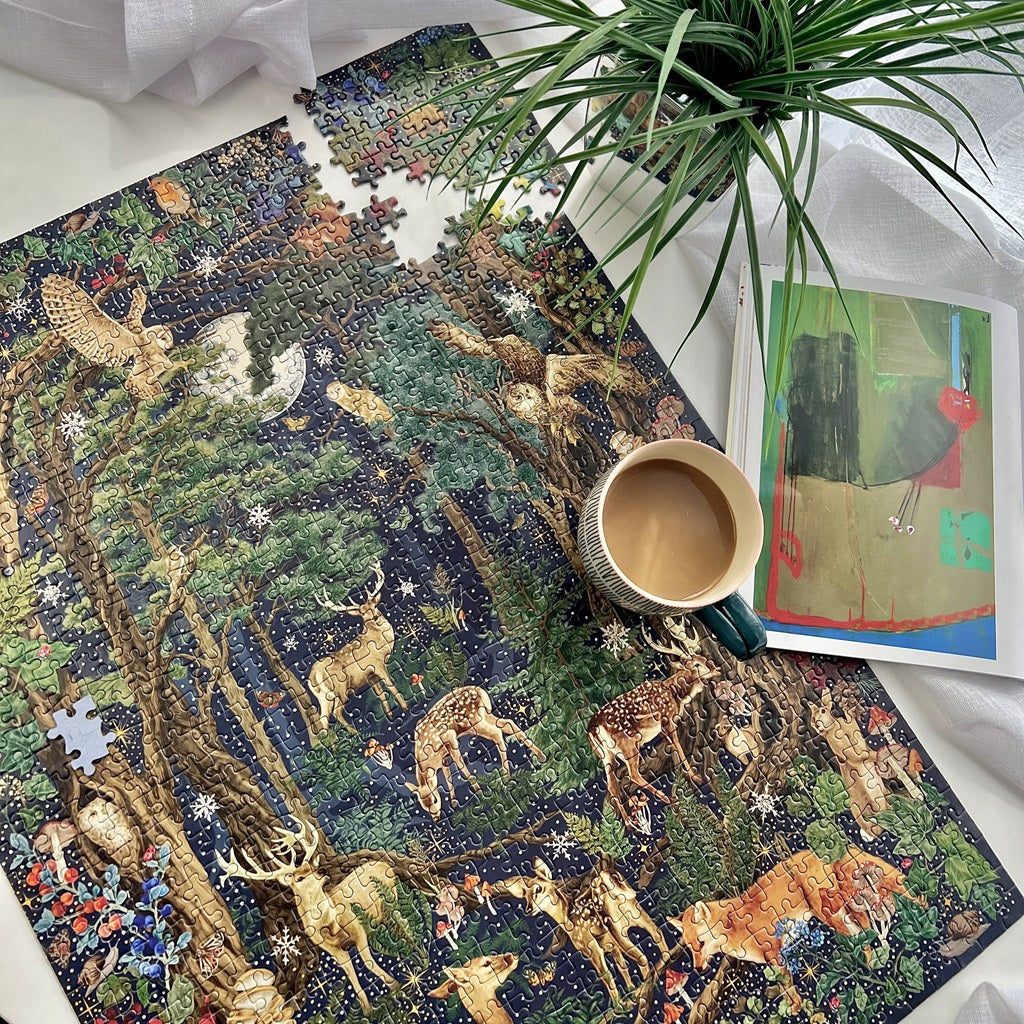Art File Into the Forest 1000 Piece Puzzle on the table with cup of coffee and plant