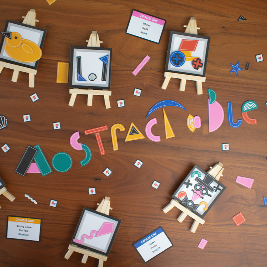 Colorful abstract shapes and art supplies on a wooden surface with 'Abstract' text.