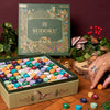 Sudoku game set with colorful pegs on a wooden surface, surrounded by decorative plants and a butterfly.
