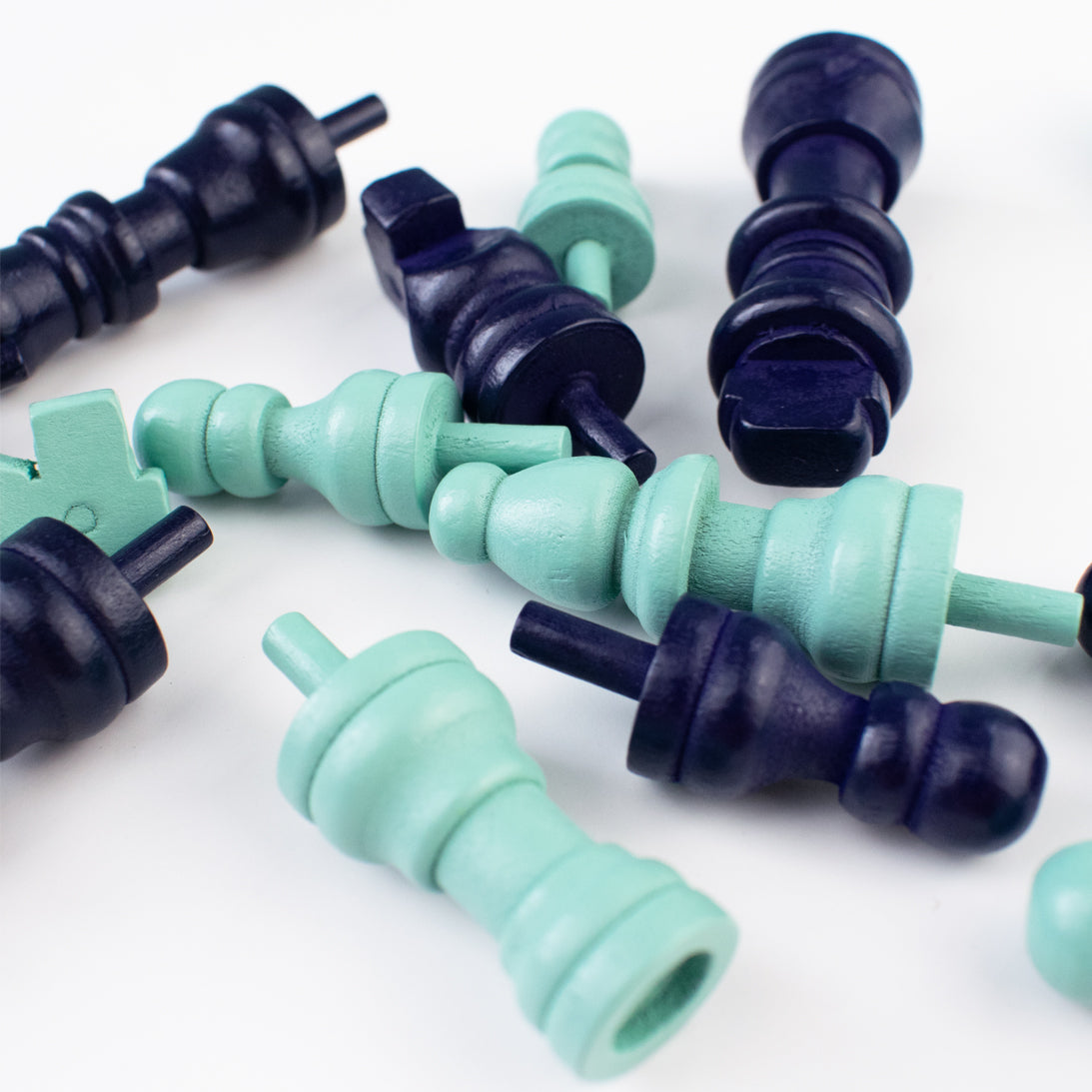 Teal and purple wooden chess pieces on a white background