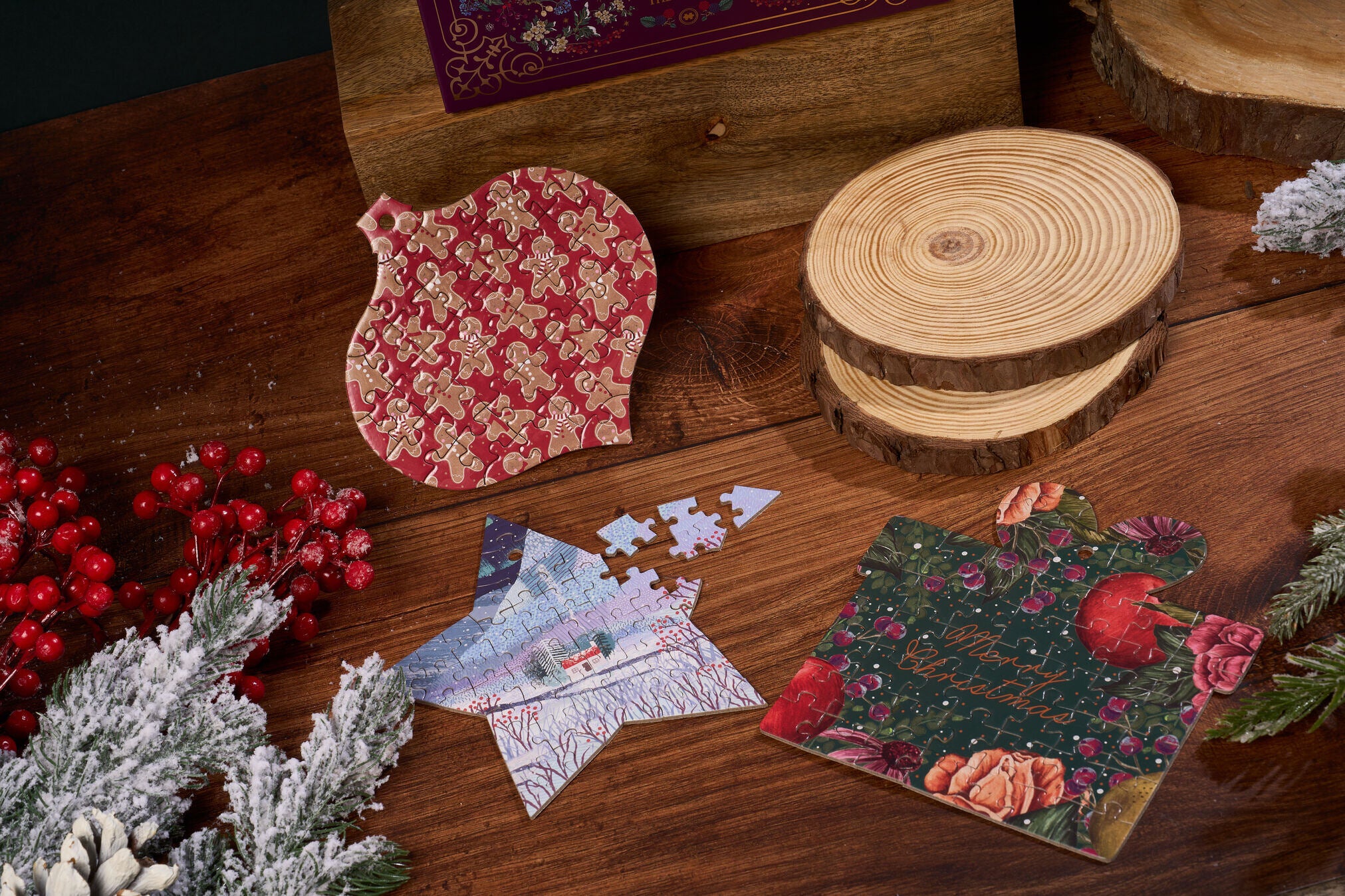 Decorative jigsaw puzzles with floral patterns on a wooden surface with Christmas decorations.