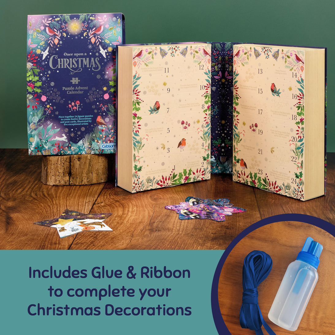 A Christmas advent calendar set displayed on a wooden table against a dark green wall. The set includes a decorative box labelled 'Your evening a Christmas Advent Calendar' on a small wood block, two open illustrated books showing numbered doors, and several colourful puzzle pieces scattered in front. Including ribbon and glue