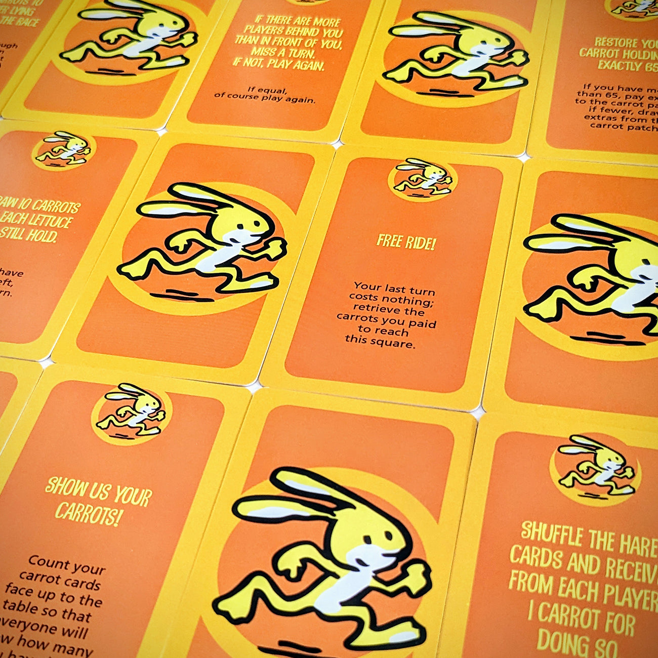 A close-up of a card game board featuring bright orange cards with a cartoon rabbit illustration and game instructions printed in yellow and black text.