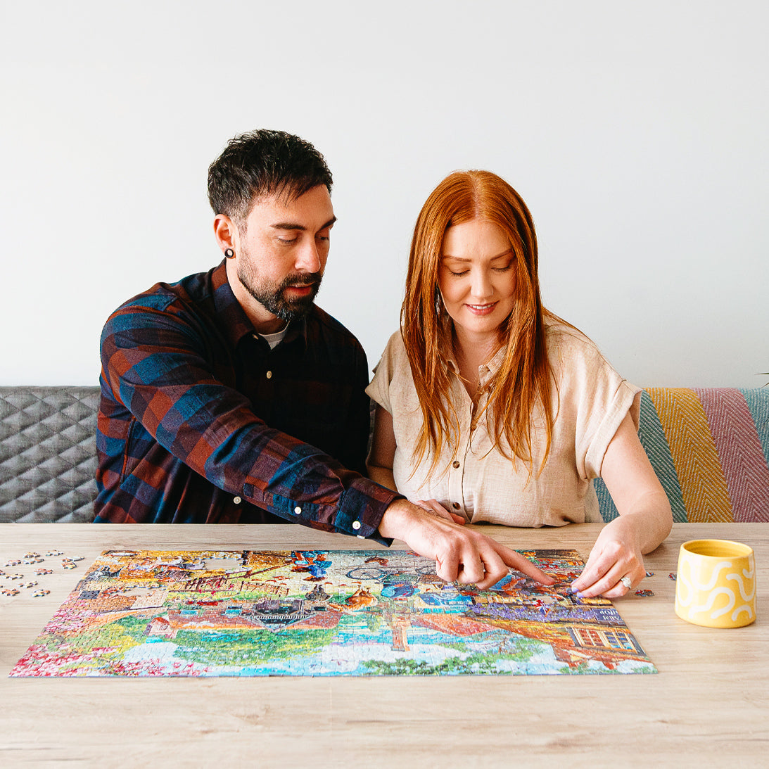 Man and woman working on a puzzle together at a table.