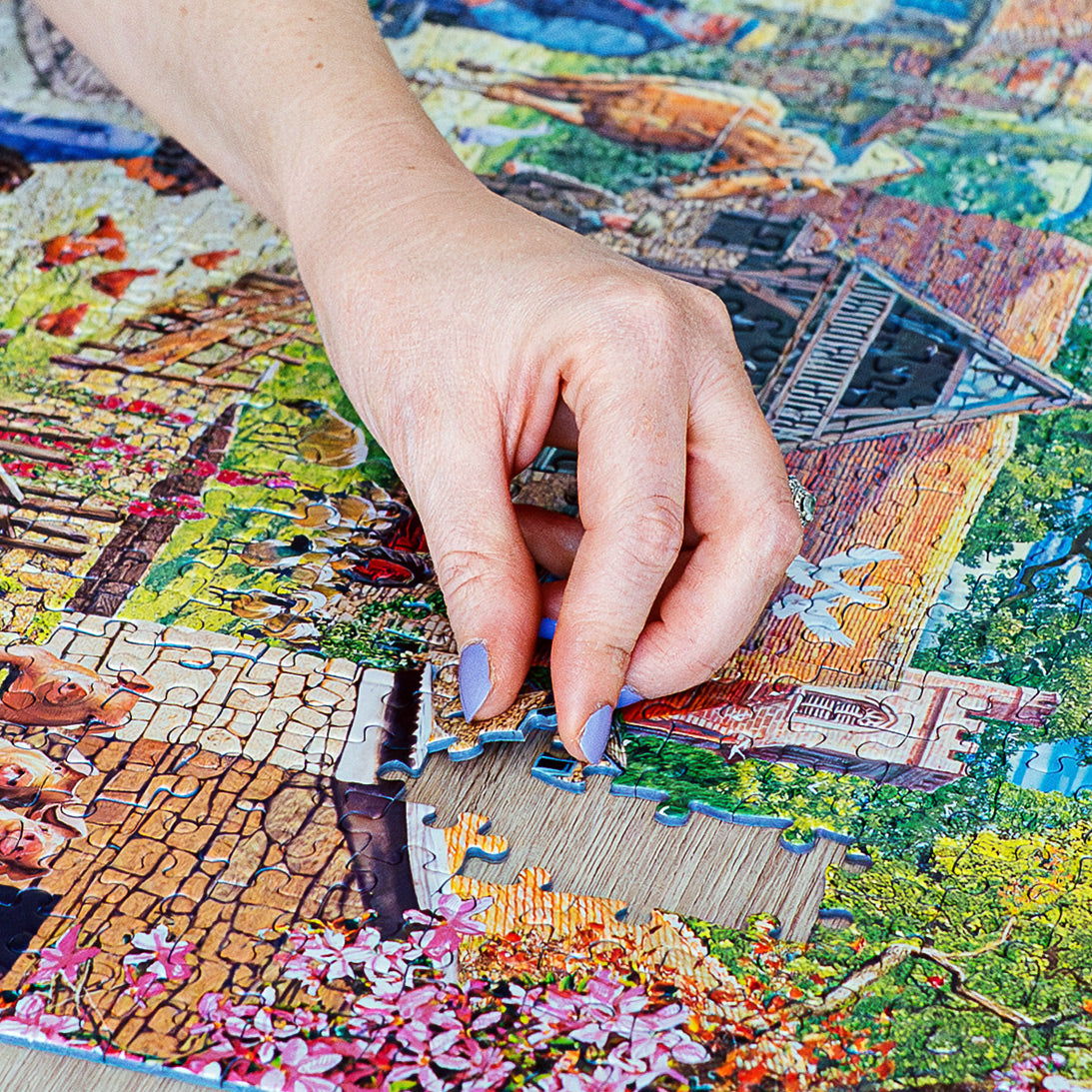 Hand placing a puzzle piece on a colorful puzzle with a scenic design.