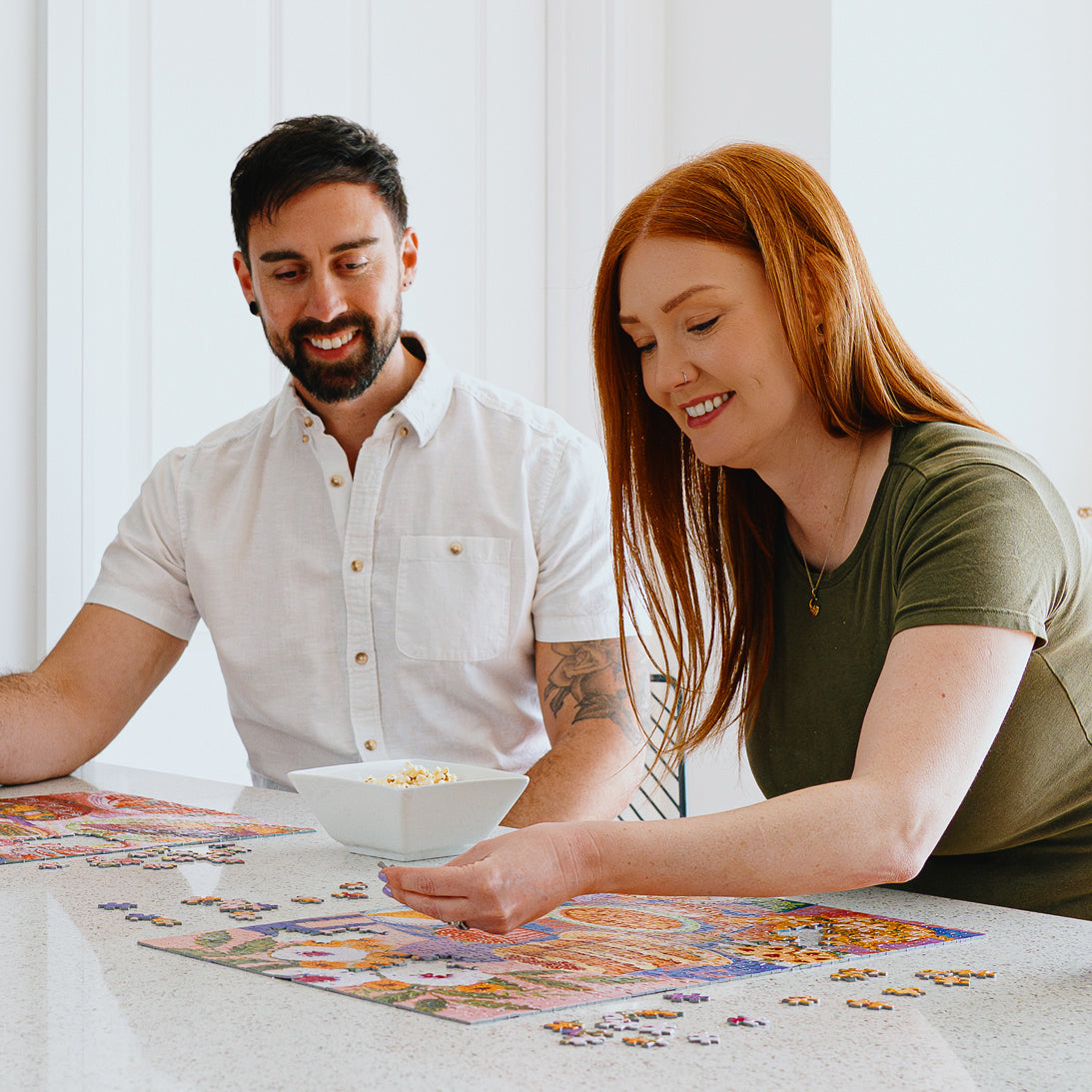 Man and woman working on a puzzle together at a table.