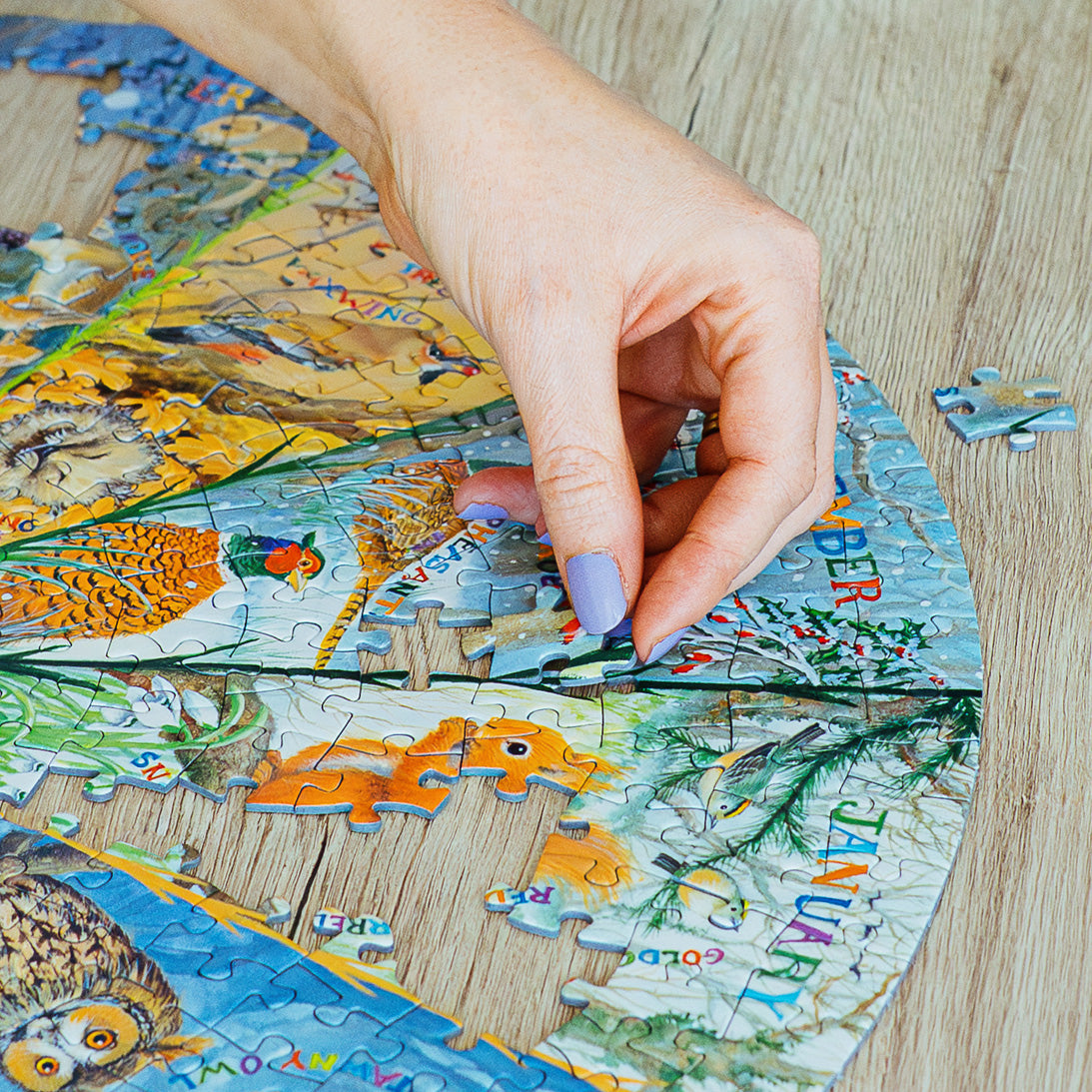 Hand placing a puzzle piece on a partially completed puzzle with a nature-themed design.