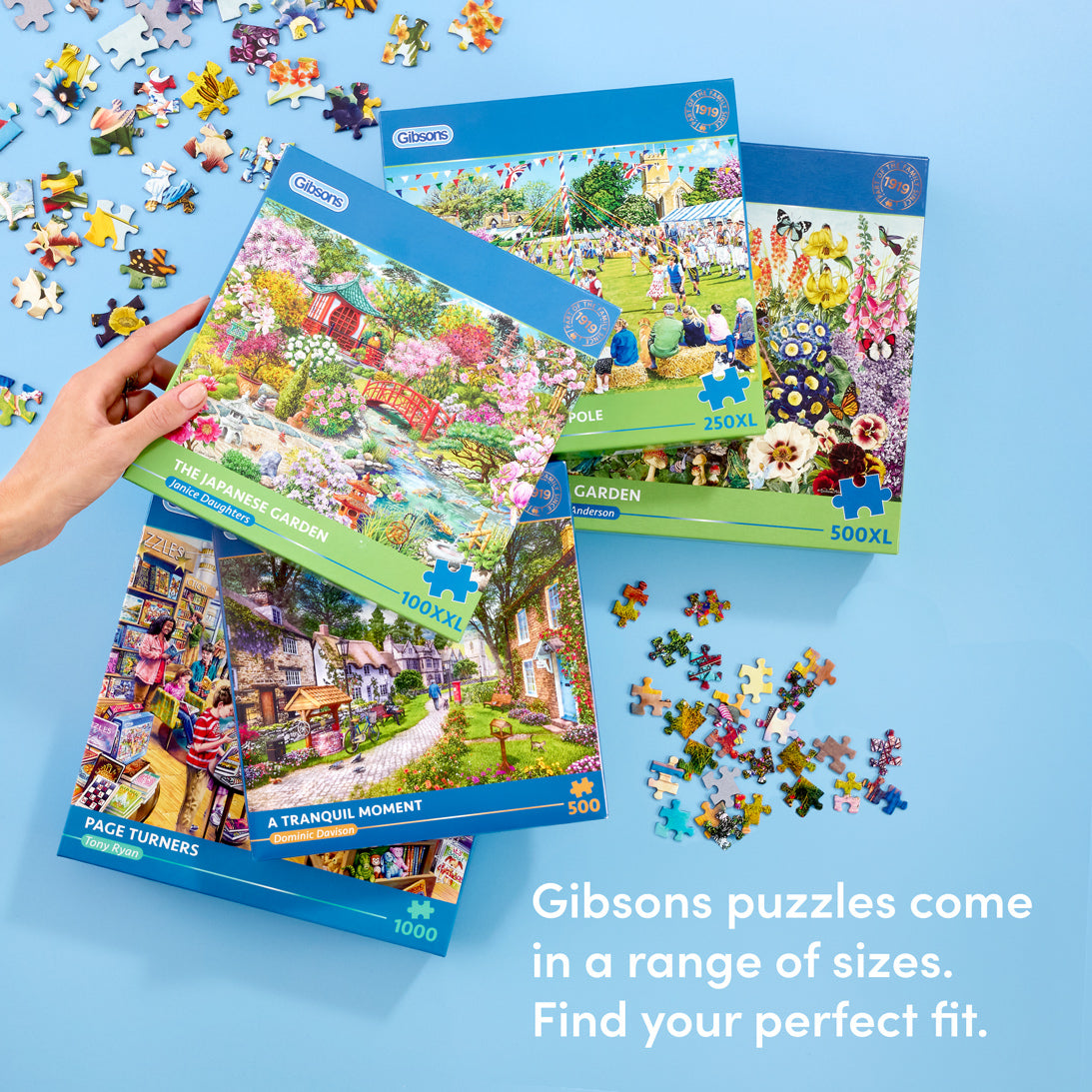 Gibsons puzzles with colorful packaging and scattered puzzle pieces on a blue background