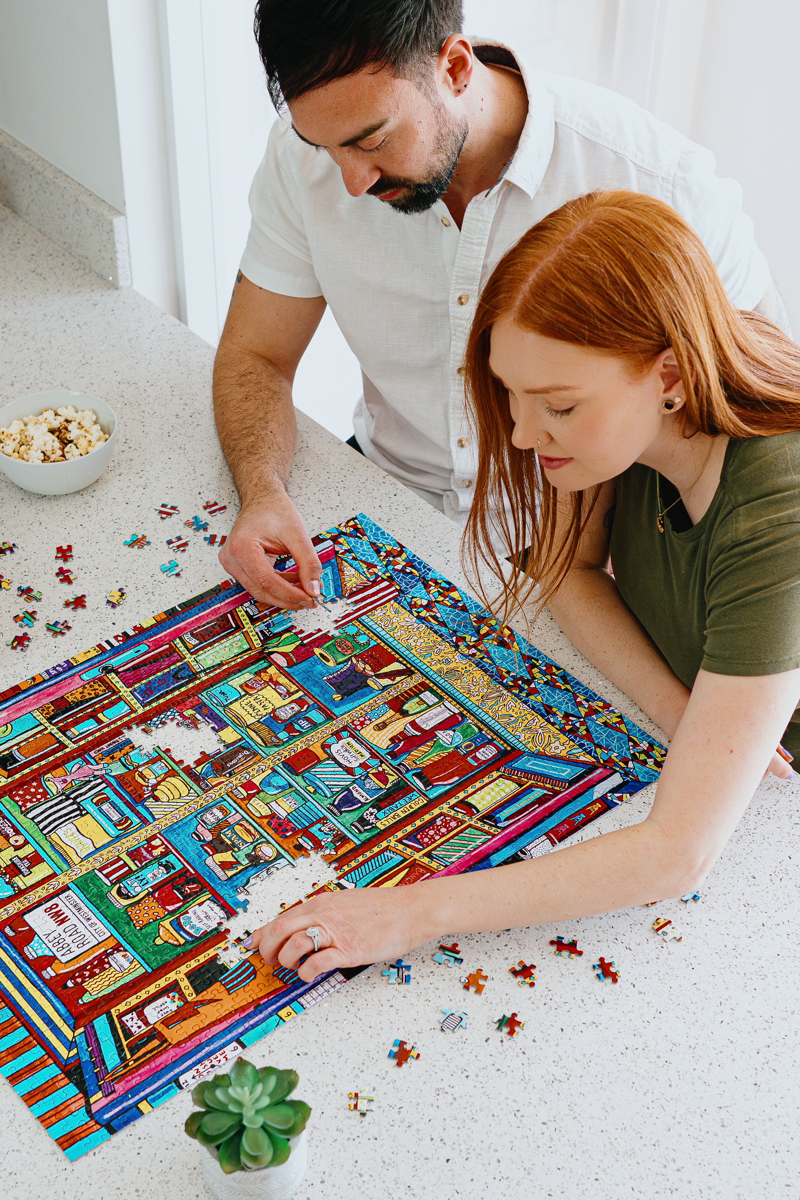 Man and woman working on a colorful puzzle together.
