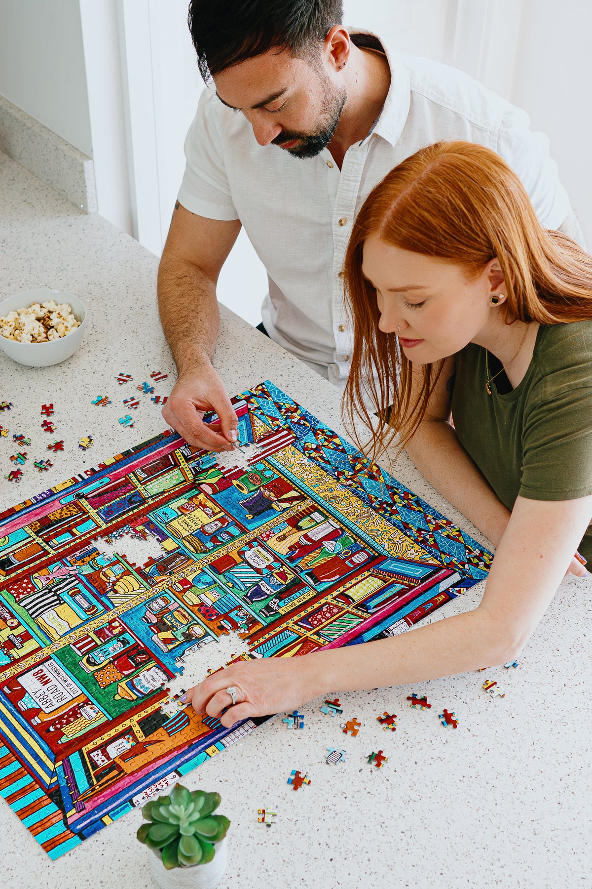 Man and woman working on a colorful puzzle together.