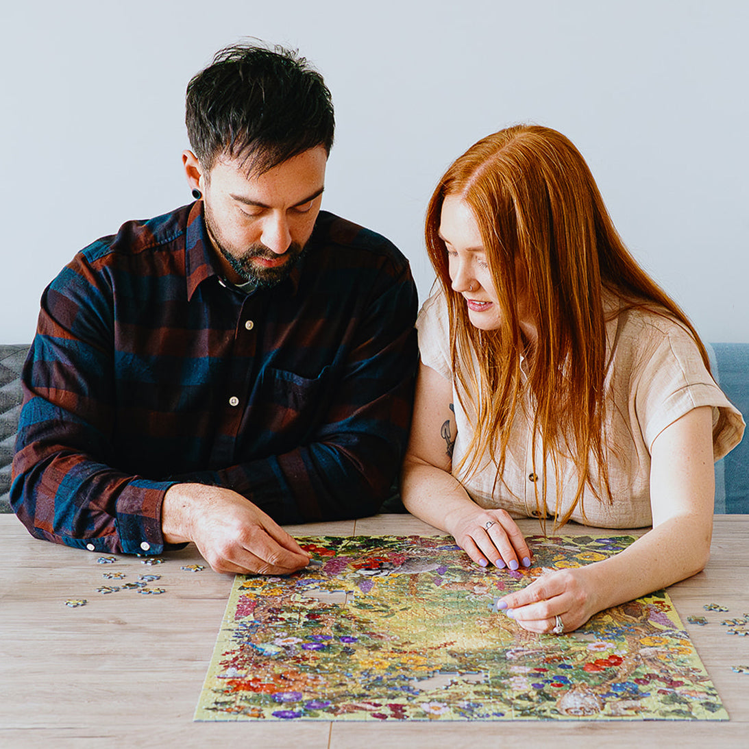 Man and woman working on a puzzle together at a table.