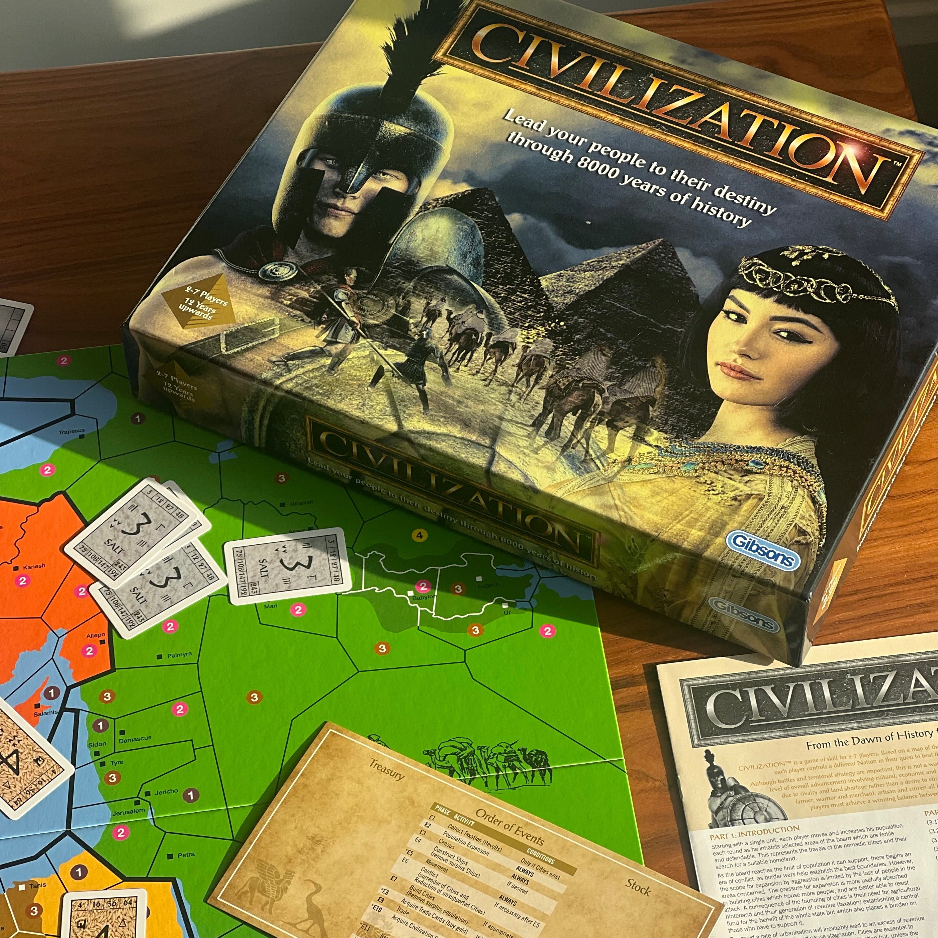 Civilization board game box displayed on a wooden table with the game board, cards, and informational sheet spread out in front. The box art shows an ancient Egyptian scene with a pharaoh and pyramids, and the Civilization title is clearly visible.