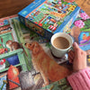 Gibsons Puzzle Subscription 1000 piece jigsaw unpacked and completed with a person holding a hot beverage.